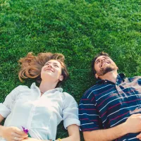 man and woman laying in the grass looking at the sky