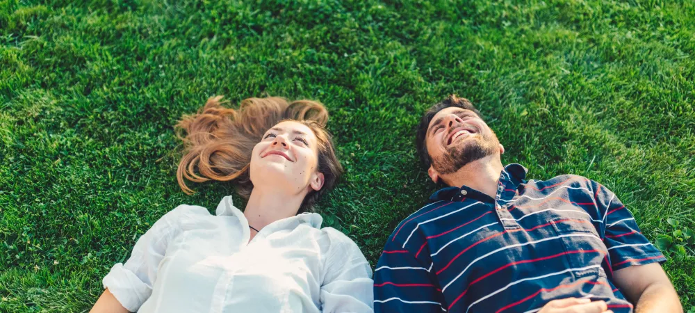 man and woman laying in the grass looking at the sky
